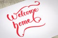 Welcome Home creative brush lettering in red color.