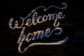 Welcome Home wooden calligraphy lettering on black.