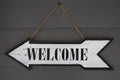 Welcome inscription on arrow sign. Rustic vintage pointer on wall photo closeup. Weathered wooden texture, welcome word