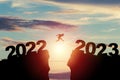 Welcome merry Christmas and happy new year in 2023,Silhouette Man jumping from 2022 cliff to 2023 cliff with cloud sky and