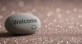 Welcome message on smooth stone with a smile on a glittery surface Royalty Free Stock Photo