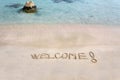 Welcome message written on white sand, with tropical sea waves in background Royalty Free Stock Photo