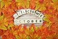 Welcome October alphabet letter with maple leaves frame on wooden background