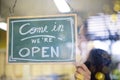 Welcome. Open. barista, waitress woman turning open sign board on glass door Royalty Free Stock Photo