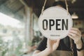 Welcome. Open. barista, waitress woman turning open sign board on glass door in modern cafe coffee shop Royalty Free Stock Photo