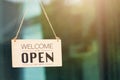 WELCOME WE ARE OPEN PLEASE COME IN notice sign wood board label hanging through glass door Royalty Free Stock Photo