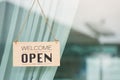 WELCOME WE ARE OPEN PLEASE COME IN notice sign wood board label hanging through glass door Royalty Free Stock Photo