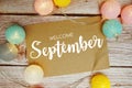 Welcome September card typography text with LED cotton ball on wooden background Royalty Free Stock Photo