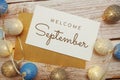 Welcome September card typography text with LED cotton ball on wooden background Royalty Free Stock Photo