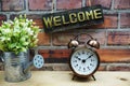 Welcome sign hanging with alarm clock on old brick wall background Royalty Free Stock Photo