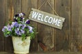 Welcome sign hanging by pot of purple flowers (pan Royalty Free Stock Photo