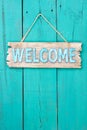 Welcome sign hanging on teal blue wood door