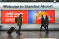 Welcome sign in London Stansted Airport with travellers passing by