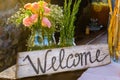 Welcome sign painted on wood next to pink flowers Royalty Free Stock Photo