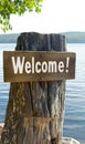 Welcome sign on wooden post by lake