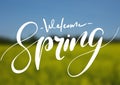Welcome spring handwriting lettering design on blurry blossom field landscape.