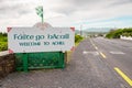 Welcome to Achill sign in Irish and English language by road. Travel and tourism information. Cloudy sky. Small county colors flag Royalty Free Stock Photo