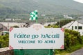 Welcome to Achill sign in Irish and English language by road. Travel and tourism information. Cloudy sky. Small county colors flag Royalty Free Stock Photo