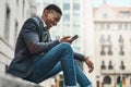 Welcome to Avenue Success. Shot of a young businessman sitting on the curb and using a smartphone against an urban Royalty Free Stock Photo