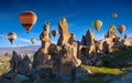 Welcome to Cappadocia concept image. Hand carved rooms in limestone rocks in Cappadocia, Turkey. Hot air balloons fly in blue sky Royalty Free Stock Photo