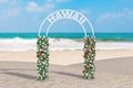 Welcome to Hawaii Concept. Beautiful Decor Arc, Gate or Portal with Flowers and Hawaii Sign on an Ocean Deserted Coast. 3d