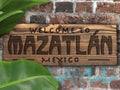 Welcome to Mazatlan Mexico Wood Sign on Brick wall with palm leaves and graffiti