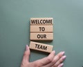 Welcome to our team symbol. Concept words Welcome to our team on wooden blocks. Beautiful grey green background. Businessman hand Royalty Free Stock Photo