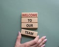 Welcome to our team symbol. Concept words Welcome to our team on wooden blocks. Beautiful grey green background. Businessman hand Royalty Free Stock Photo