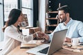 Welcome to our team! Young modern colleagues in smart casual wear shaking hands and smiling while working in the office Royalty Free Stock Photo