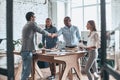 Welcome to our team. Young modern men in smart casual wear shaking hands while standing with their colleagues in the board room Royalty Free Stock Photo