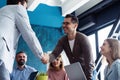 Welcome to our team! Young modern men in smart casual wear shaking hands while working in the creative office. Royalty Free Stock Photo