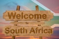 Welcome to South Africa sign on wood background with blending national flag