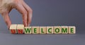 Welcome or unwelcome symbol. Businessman turns wooden cubes and changes the word unwelcome to welcome. Beautiful grey table, grey