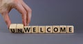 Welcome or unwelcome symbol. Businessman turns wooden cubes and changes the word unwelcome to welcome. Beautiful grey table, grey
