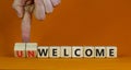 Welcome or unwelcome symbol. Businessman turns wooden cubes and changes the word unwelcome to welcome. Beautiful orange table, Royalty Free Stock Photo