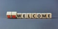 Welcome or unwelcome symbol. Turned wooden cubes and changed the word unwelcome to welcome. Beautiful grey table, grey background Royalty Free Stock Photo