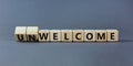 Welcome or unwelcome symbol. Turned wooden cubes and changed the word unwelcome to welcome. Beautiful grey table, grey background