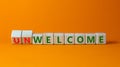 Welcome or unwelcome symbol. Turned wooden cubes and changed the word unwelcome to welcome. Beautiful orange table, orange Royalty Free Stock Photo