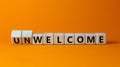 Welcome or unwelcome symbol. Turned wooden cubes and changed the word unwelcome to welcome. Beautiful orange table, orange Royalty Free Stock Photo