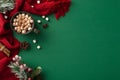 Top-view vertical picture of a lavish cocoa cup, marshmallow, spices, pine cone, mistletoe berries, scarf on a green surface