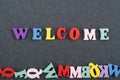 WELCOME word on black board background composed from colorful abc alphabet block wooden letters, copy space for ad text. Learning