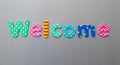 Welcome word spelled out in bright colorful patterened letters on brushed metal background Royalty Free Stock Photo