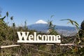 Welcome - Word written in wood. Background with Fuji City aerial view and the famous Mount Fuji with snowy peak, Japan Royalty Free Stock Photo