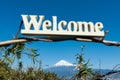 Welcome - Word written in wood. Background with Fuji City aerial view and the famous Mount Fuji with snowy peak Royalty Free Stock Photo