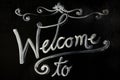 Welcome written on chalkboard with black plant,.