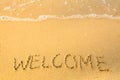 Welcome, written in sand on beach texture, soft wave of the sea. Travel. Royalty Free Stock Photo