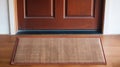 welcoming entrance a polished wooden door and a textured, warm toned doormat that invites guests into the home