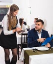 Welcoming female waiter is taking order from businessman in restaurante Royalty Free Stock Photo