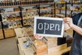 Cropped shot of male owner in apron holding open chalkboard in hands.