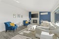 Welcoming living room with a blue accent wall, white faux fur pillows and a modern fireplace